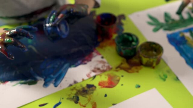 Children draw with finger paints in kindergarten or home, close up. Concept of child development.