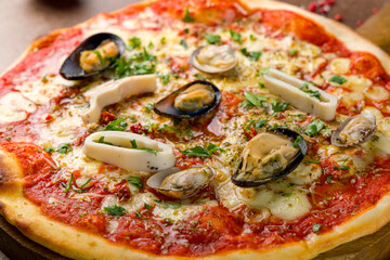 Pizza with seafood, cheese and tomato sauce on wooden board macro close up