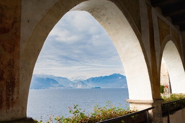 Arcade in the famous "Eremo di Santa Caterina del Sasso" (meaning: "Saint Catherine of the stone hermitage"). Blue waters of Lake Maggiore on the background, with italian alps, Italy.