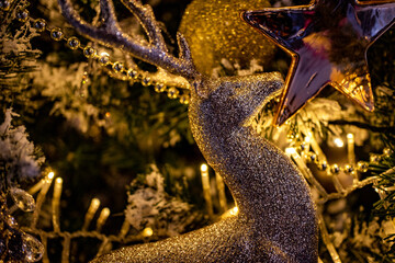 Warm and cozy evening in the Christmas tree design. The Christmas tree is decorated with lights and toys. Lanterns, garland lighting in the room. Hight quality photo