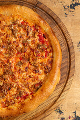 Meat pizza on a wooden table.