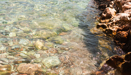 Sea stones in the sea at summer sunny day. Nautical background of pebbles. Seascape. Selective focus.