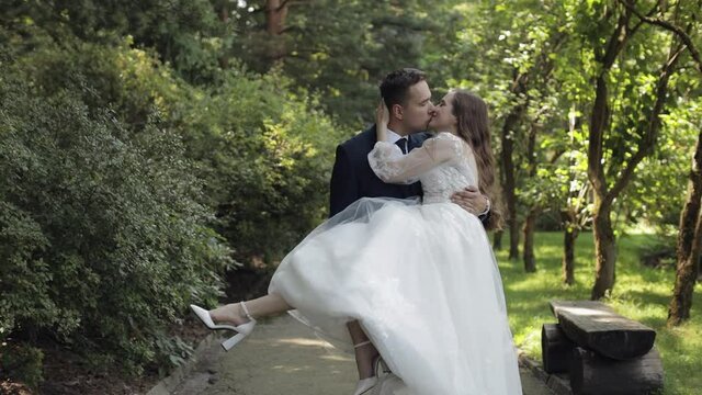 Newlyweds. Lovely Caucasian bride groom dancing in park. Making kiss. Happy wedding couple family. Romantic love of man and woman. Bride in gorgeous wedding dress. Bridegroom in jacket. Slow motion