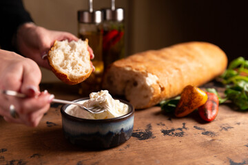 Stracciella cheese in a plate. The hand puts on the bread.