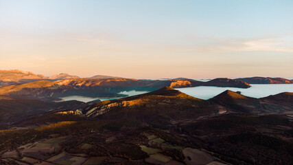 Aerial view of a sea of ​​clouds between the mountains during sunset
