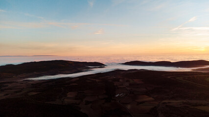 Aerial view of a sea of ​​clouds between the mountains during sunset