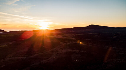 Fototapeta premium Aerial view of a sea of ​​clouds between the mountains during sunset