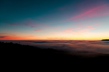 Naklejka na ściany i meble Sunset seen from the top of the mountain in a sea of ​​clouds