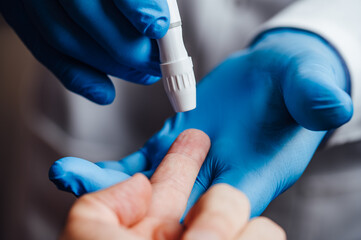 Doctor about to pierce a patient's finger with a lancet - obrazy, fototapety, plakaty