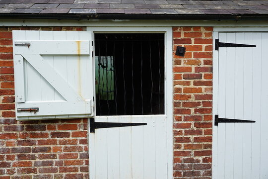 farm stables with hinged door and windows. Rustic farm out building used for storage. 