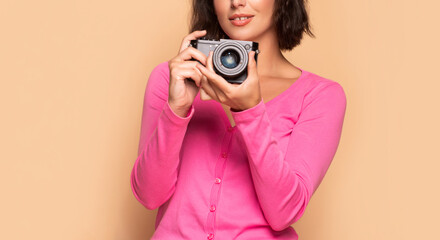 Obraz premium Woman photographer crop view holding photo camera in hands beige background, photographing