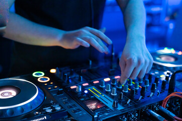Close-Up of Dj Mixer Controller Desk in Night Club Disco Party. DJ Hands touching Buttons and Sliders Playing Electronic Music . High quality photography.