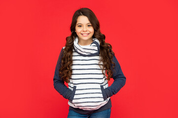 winter fashion. positive kid with curly hair in fleece jacket. teen girl on red background.