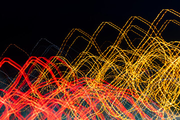 Blurred moving red and yellow lights on a german Autobahn seen through the windshield while driving at night. Lines and light traces caused by camera shake at high speed. 