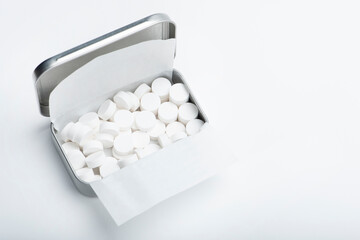 Mint candies on a white background. White mint candies in an open tin box. Fresh breath or bad...