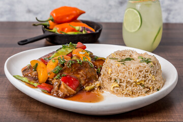 tenderloin cubes sautéed in soy sauce onion tomato coriander with French fries and rice on gray marble