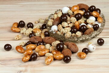 Assorted chocolate and coated candies. Delicious sweets placed in a bowl on the wooden table.