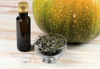 Oil pumpkin seeds and bottle of pumpkin oil. The whole pumpkin at the background. Oil pumpkin is...
