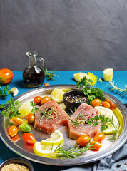 Fresh tuna steaks on the iron dish with herbs, spices and vegatable