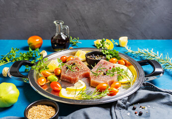 Fresh tuna steaks on the iron dish with herbs, spices and vegatable