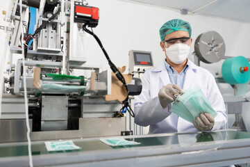 male factory worker are producing medical face masks, counting and checking of quality from machine