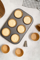 cupcake mold with dough on the grey background. Vertical frame.