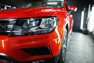 Headlight of nice and new orange sport suv car in modern garage. - Powered by Adobe
