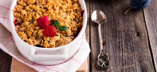 Plum and raspberry crumb on the old wooden background. Rustic style. Selective focus.