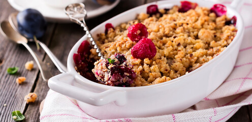 Plum and raspberry crumb on the old wooden background. Rustic style. Selective focus.