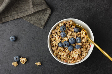 Granola with blueberry in white bowl.