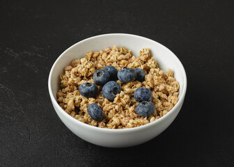 Granola with blueberry in white bowl.