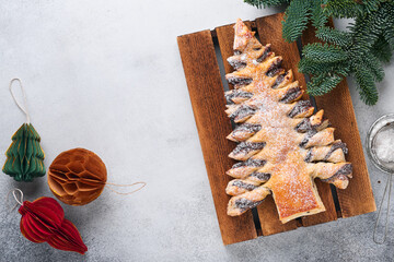 Puff pastry Christmas tree with chocolate paste, sprinkled with powdered sugar on a gray...