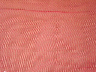 Pink tulle in a fold on a red background as a backdrop. High quality photo