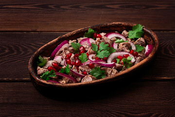 Traditional Georgian cuisine, Kuchmachi, chicken giblets, in ketsi, on a wooden table, close-up, horizontal, no people,