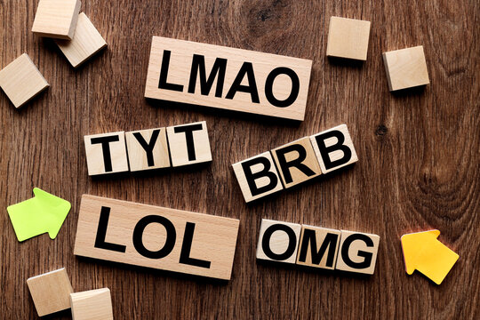 LMAO, TYT Take your time, BRB Be Right Back, Be Right Back, LOL, Lots of Laughs, OMG, Oh my God, text message abbreviation on wooden cubes in the shape of a crossword puzzle. Internet slang.