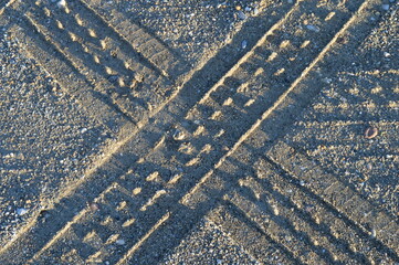 traces of truck tires in the sand that intersect perfectly in the shape of the letter x