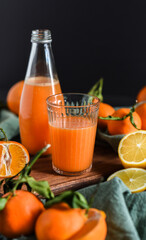 Frisch gepresster Orangensaft im Glas mit Citrusfrüchten auf dunklem Hintergrund. Fruchtiges Stillleben auf schwarzen Hintergrund mit frischen Früchten