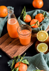 Frisch gepresster Orangensaft im Glas mit Citrusfrüchten auf dunklem Hintergrund. Fruchtiges Stillleben auf schwarzen Hintergrund mit frischen Früchten