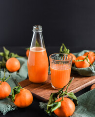 Frisch gepresster Orangensaft im Glas mit Citrusfrüchten auf dunklem Hintergrund. Fruchtiges Stillleben auf schwarzen Hintergrund mit frischen Früchten