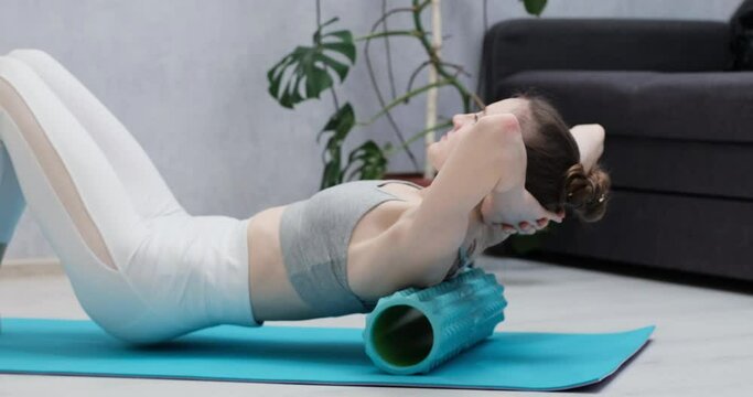 Myofascial release massage womans back. Girl doing back muscles exercise using foam roller. MFR
