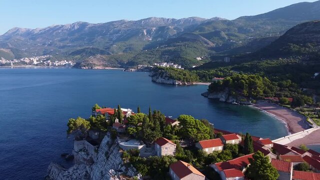 Coast of the sea, covered with mountains with dense forests. Aerial view of island in sunny weather. Drone Shot of Sveti Stefan (Saint Stephen)in Montenegro.