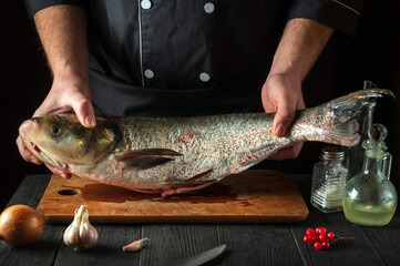 The chef prepares silver carp fish. Preparing for the preparation of fish food for the holidays. Working environment in the restaurant kitchen