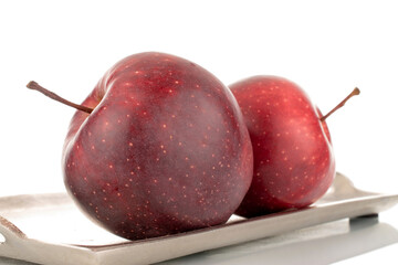 Two organic sweet red apples with a tray of metal, close-up, isolated on white.