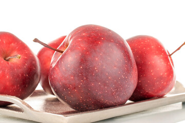 Several organic sweet red apples with a tray of metal, close-up, isolated on white.
