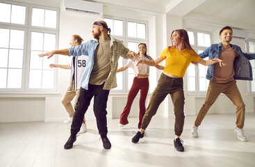 Millennial diverse dancing group or crew training exercising together in studio. Young teen dancers in casual clothes perform prepare for concert. Hobby and entertainment concept.