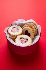 Red box with heart shaped linzer cookies on red background. Mother's day, Women's day, Valentine's day. Homemade present. Copy space, top view. Selective focus.