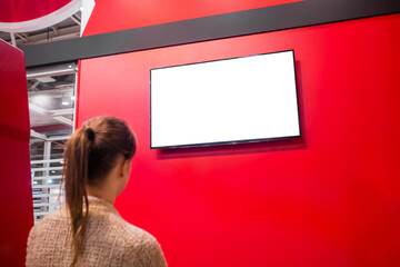 Woman looking at blank digital interactive white display on red wall at exhibition or museum with...