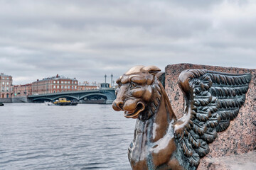 St.Petersburg, Russia. Sculpture of mythical griffin on embankment and bridge across Neva river.