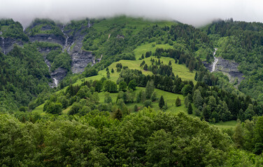 Panoramic view on mountain waterfalls, green forests and apline meadows near Saint-Gervais-les-Bains, Savoy. France