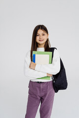 Portrait of teenager girl with school backpack holding colored folders on white background